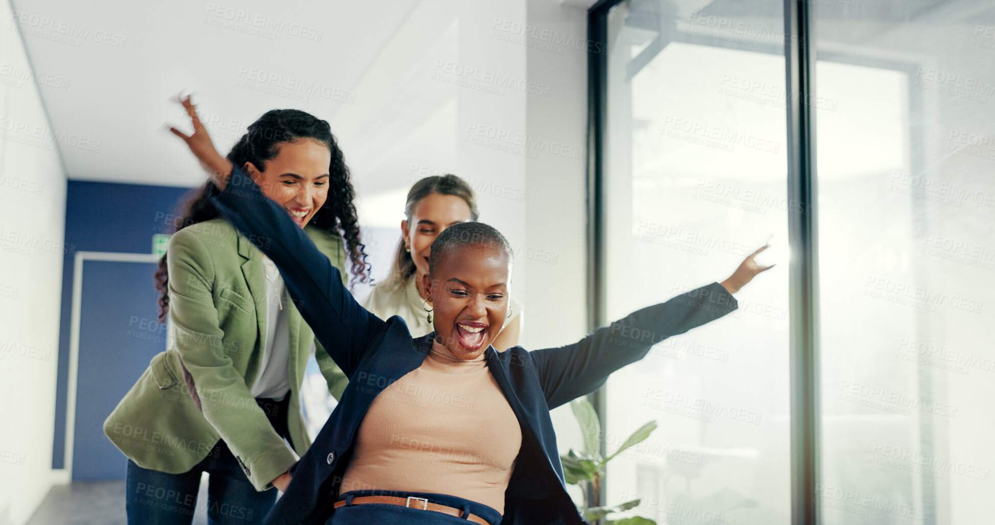 Buy stock photo Office, celebration or professional women push chair for happiness, investment growth or startup success in company corridor. Diversity, fun and people with excited face for playing and achievement