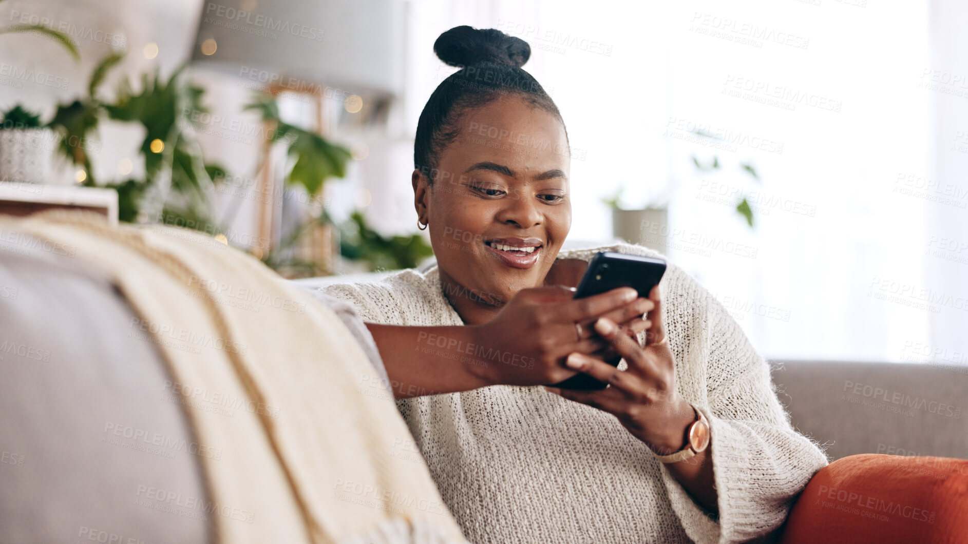 Buy stock photo Black woman, reading and using phone with smile in home or social media, mobile app and communication online.  Funny, meme or person on couch streaming video or typing on cellphone in living room