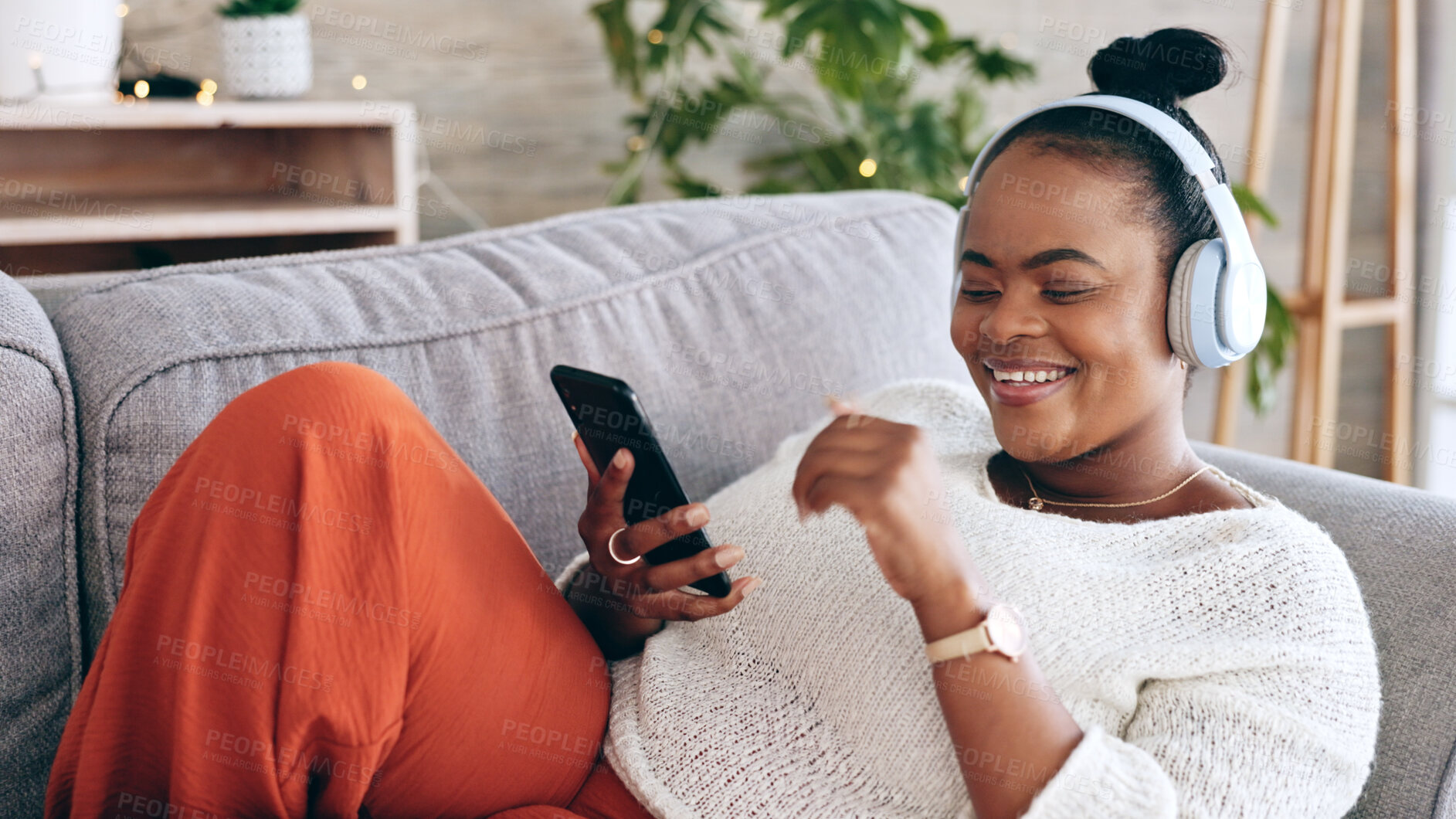 Buy stock photo Black woman on couch, headphones for music and smartphone, relax at home and audio streaming with smile. Happiness, mobile app and using phone for radio or podcast, scroll with technology in lounge