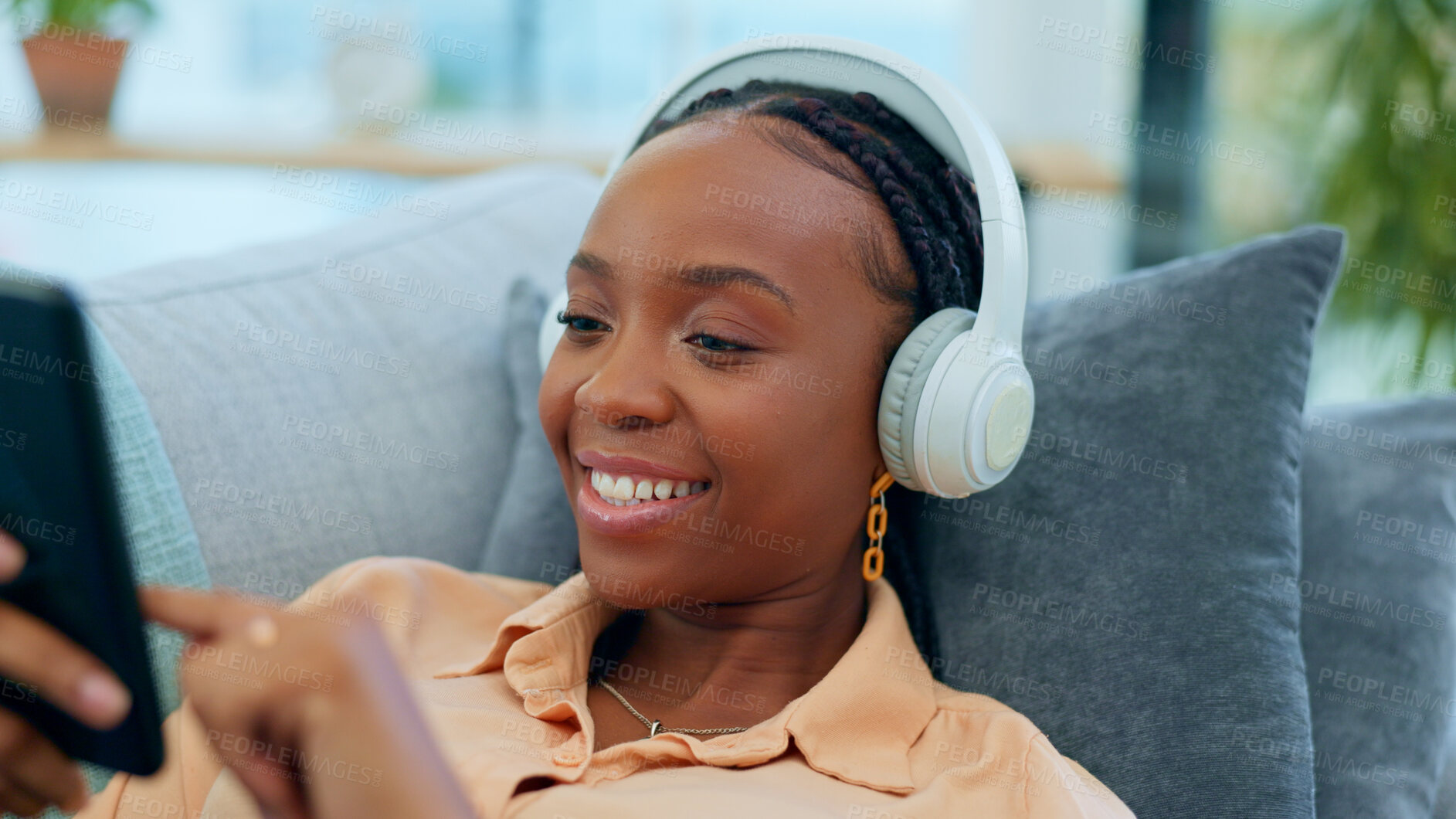 Buy stock photo Happy black woman, headphones and relax on sofa with phone listening to music or podcast at home. Face of African female person smile with headset for audio streaming or sound on living room couch