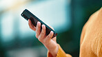 Closeup female entrepreneurs hands texting on a phone outside standing in a park with bokeh lights. Businesswoman browsing online and typing emails on mobile technology while using an app outside