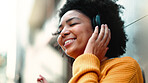 Black woman with headphones for listening to music in city for travel, motivation and happy mindset. Young person on an urban street with buildings background while streaming podcast or audio outdoor