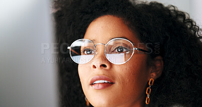 Businesswoman with trendy glasses reading information on a computer screen while working in an office. Closeup of one confident entrepreneur smiling while carefully analyzing reports and plans online