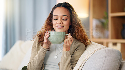 Woman drinking a hot cup of tea or coffee at home. Carefree, relaxed and cheerful young female smelling the aroma of a fresh warm beverage while taking a sip and enjoying a comfortable break at home