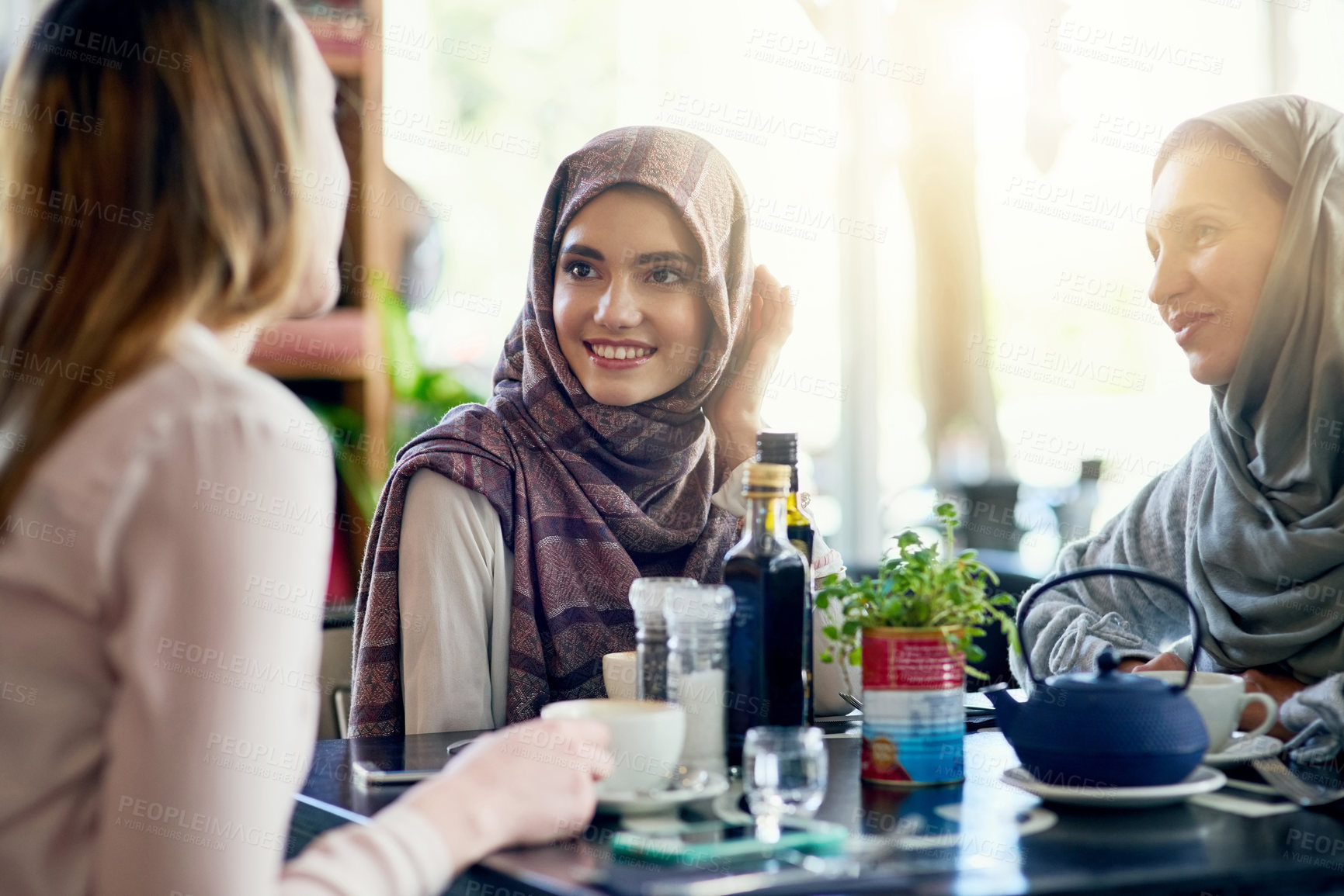 Buy stock photo Muslim women, friends and brunch in restaurant, together and talking with food, smile and discussion. Islamic woman, group and eating lunch with conversation, happy face and listen with food in cafe