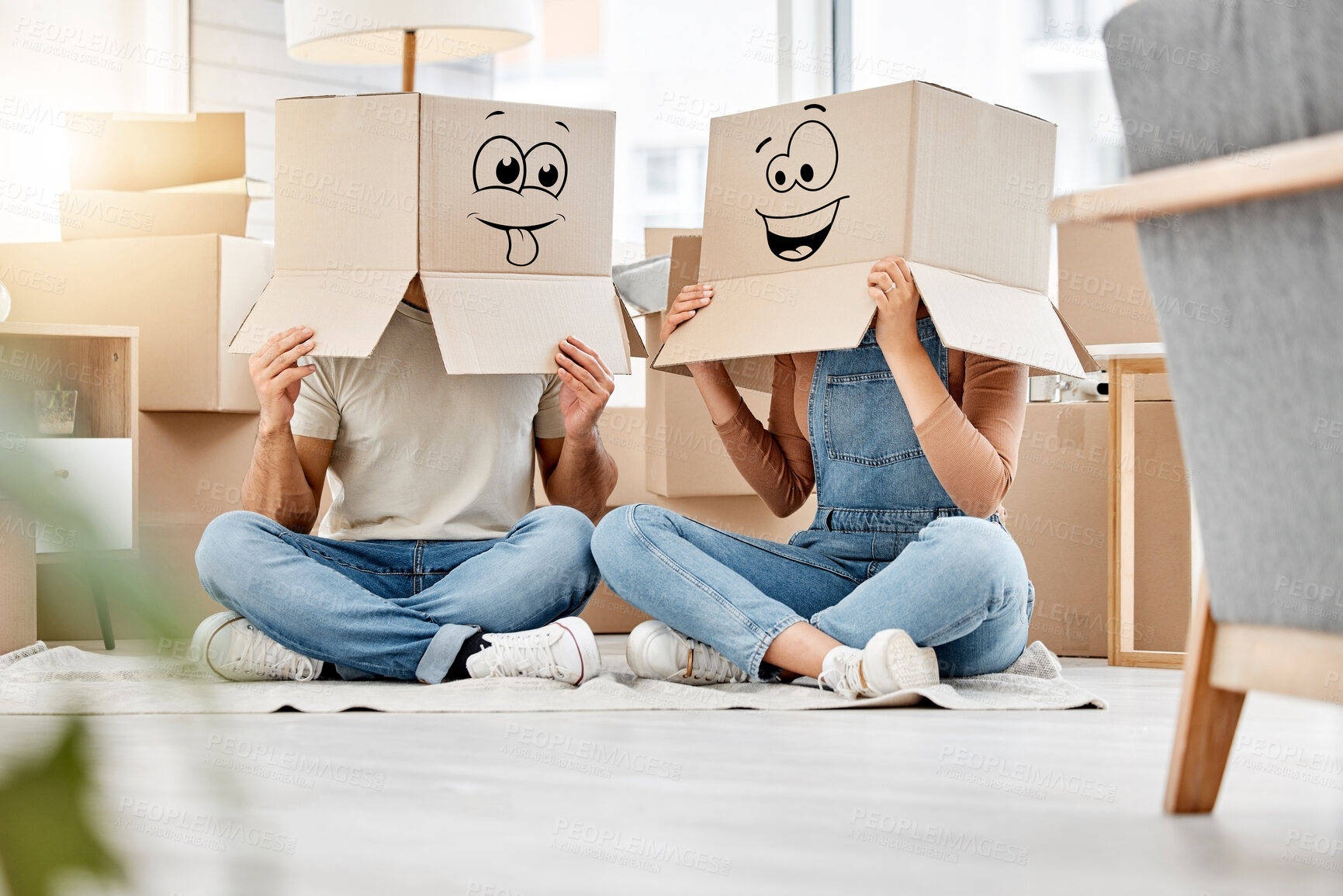 Buy stock photo Funny, couple moving and boxes on head with faces, smile or emoji drawing on cardboard and new house, property or real estate. People, comic and box on body with happiness, crazy or joke in home