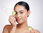 Cucumber, face and beauty of a woman in studio for skin glow, dermatology and cosmetics. Portrait of model person with a vegetable in hand for natural facial, health or wellness on a white background