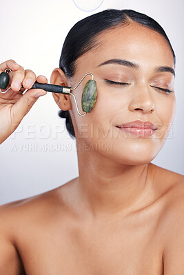 Buy stock photo Calm woman, skincare and roller in relax for beauty or cosmetics against a white studio background. Happy female person or model rolling skin with jade stone for healthy wellness or facial treatment