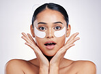 Face, eye mask and a woman in studio for beauty glow, dermatology or natural cosmetics. Portrait of surprised person with skincare patch for facial self care with wow results on a white background