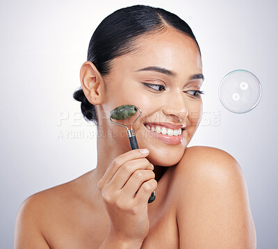 Buy stock photo Face roller, skin and a happy woman in studio for beauty glow, dermatology and natural cosmetics. Aesthetic model with tools for facial massage, skincare results and a bubble on white background