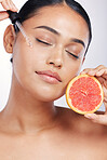 Woman, face and oil with beauty and grapefruit, skincare serum with natural cosmetics isolated on studio background. Fruit, female model with pipette and hyaluronic acid for skin with dermatology