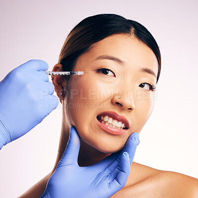 Buy stock photo Face injection, skincare and Asian woman in pain in studio isolated on a white background. Cosmetics, syringe and female model with collagen filler, dermatology and prp facelift in plastic surgery.