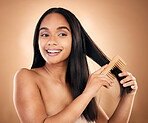 Smile, woman brush her for hair treatment and against a studio background with a glow. Self care, health wellness and cheerful or excited isolated young female person brushing against backdrop