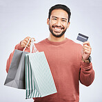 Man with smile, shopping bag and credit card with retail, discount and commercial isolated on studio background. Customer, finance and male person with payment for purchase, luxury and sale at store