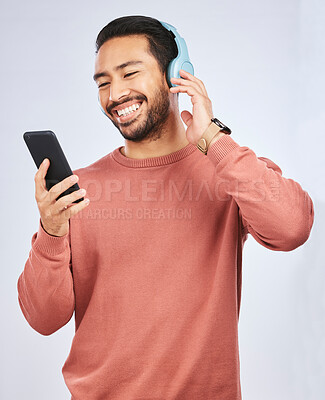 Buy stock photo Man, smile and smartphone with headphones, listening to music or podcast isolated on studio background. Male person is enjoying radio streaming, online with wireless technology and playlist on app