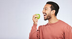 Green apple, eating and happy man isolated on a white background for healthy food, diet and detox space. Vegan person, nutritionist or asian model with fruit for self care or lose weight in studio