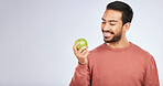 Man, apple and nutrition with health and diet, mockup space and self care isolated on studio background. Male person with smile, green fruit and organic with healthy food, detox and lose weight