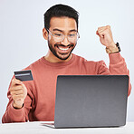 Laptop, credit card and man excited for online shopping, e commerce and payment in studio. Asian male person with technology and hand to celebrate savings win, promotion or sale on a fintech website