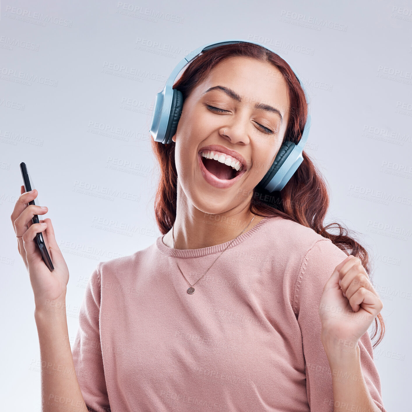 Buy stock photo Mobile, headphones or happy girl dancing to music or singing radio songs in studio on white background. Dance, smile or excited woman streaming or listening to audio playlist with cellphone or energy