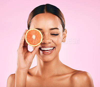 Buy stock photo Happy woman, smile and grapefruit on face for vitamin C nutrition or natural skincare against a pink studio background. Female person smiling with organic fruit for healthy diet, facial or wellness