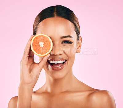 Buy stock photo Happy woman, portrait and grapefruit on face for vitamin C nutrition or natural skincare against a pink studio background. Female person smile with organic fruit for healthy diet, facial or wellness