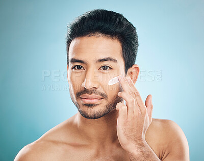 Buy stock photo Wellness, skincare and man with face cream in a studio for a natural, moisturizing and health routine. Male model with facial spf, lotion or moisturizer for dermatology treatment by a blue background