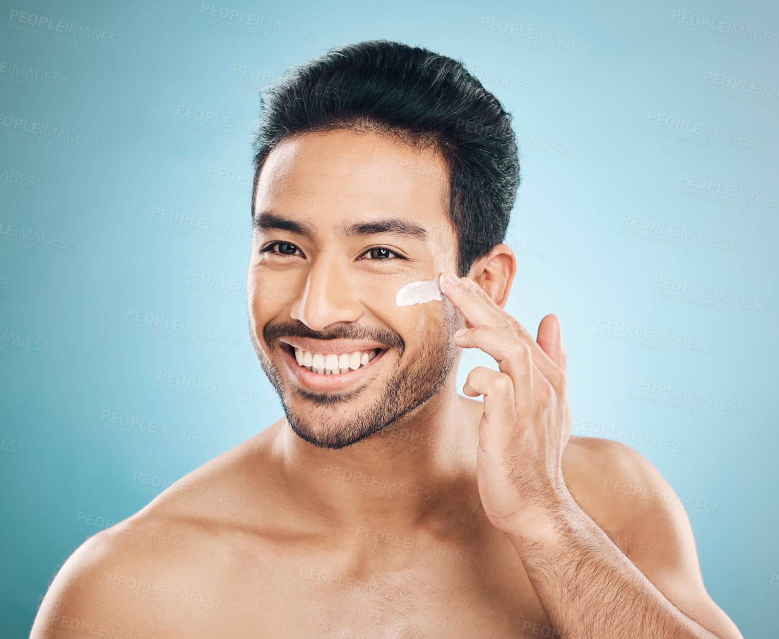 Buy stock photo Skincare, beauty and man with face cream in a studio for a natural, wellness and health routine. Happy male model with facial spf, lotion or moisturizer for dermatology treatment by a blue background