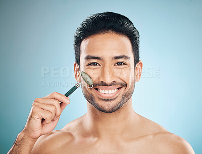 Buy stock photo Happy man, portrait or face massage with jade roller, facial product for healthy skincare on studio background. Relaxing, grooming treatment or male model smiling with dermatology cosmetics or beauty