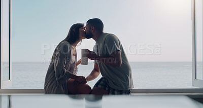 Buy stock photo Couple, kiss and coffee in morning by window with love, romance and care on holiday by ocean with sunshine. Man, woman and trust with drink, espresso or matcha on vacation by sea with bond in summer