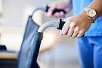 Woman, hands and closeup of wheelchair handles in nursing home for rehabilitation, help and care. Nurse, helping hand and support for person with disability in hospital, clinic or home for healthcare