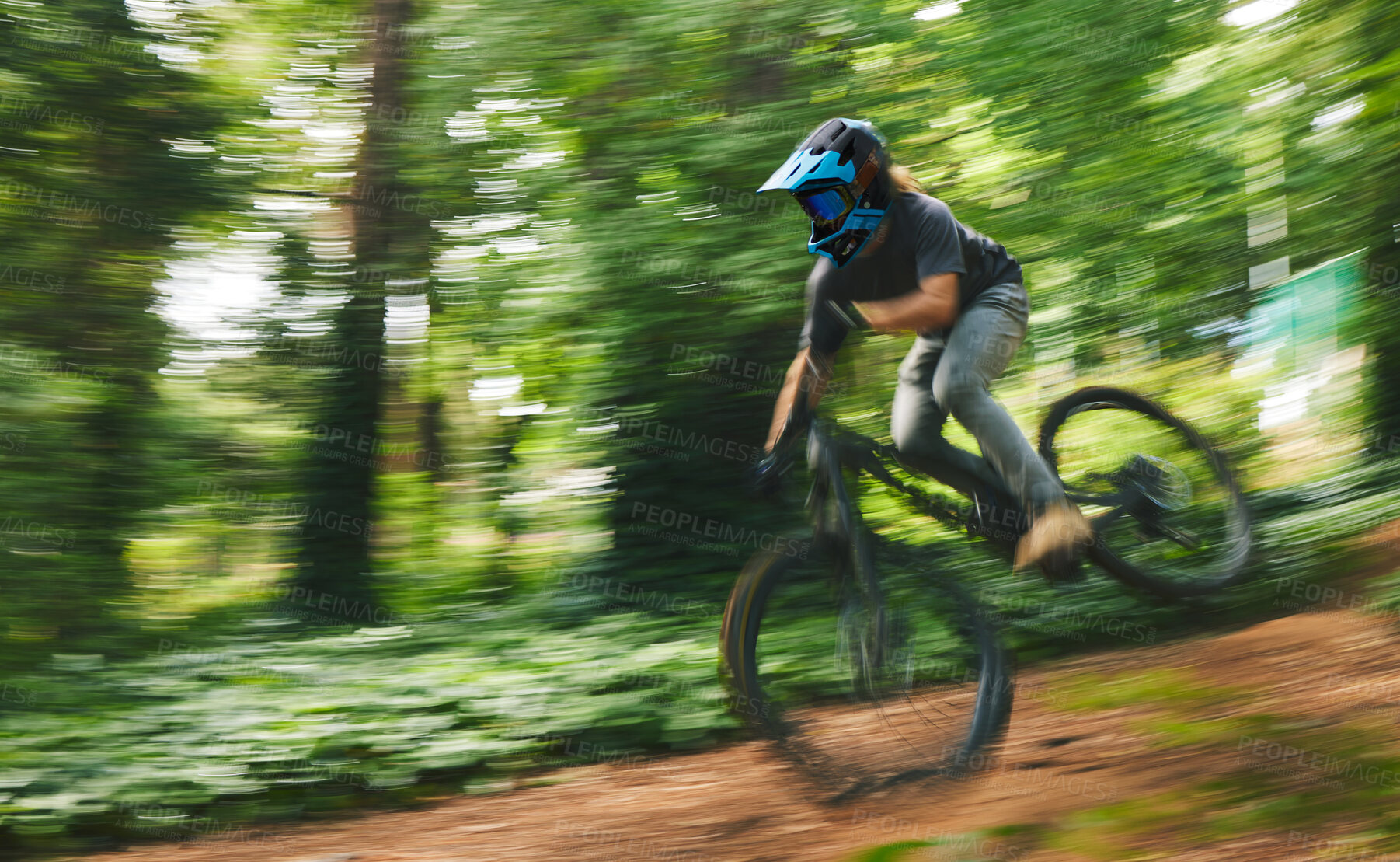 Buy stock photo Fitness, adrenaline and man doing stunt on bike while riding fast for competition practice in woods. Extreme sports, blur motion and male athlete biker training for jump skills with energy in forest.