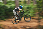 Sports, bike and man doing adrenaline stunt with energy while riding for competition practice in woods. Fitness, blur motion and male athlete biker with skill training or exercise in outdoor forest.