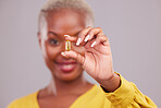 Medication, hand and woman with a pill in a studio for healthcare, wellness or recovery. Medical, medicine and closeup of an African female person with a tablet capsule isolated by a gray background.