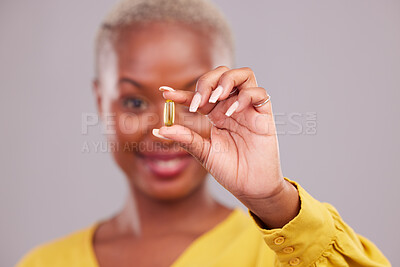 Buy stock photo Medication, hand and woman with a pill in a studio for healthcare, wellness or recovery. Medical, medicine and closeup of an African female person with a tablet capsule isolated by a gray background.
