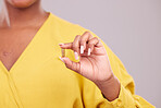 Pharmaceutical, hand and woman with a pill in a studio for healthcare, wellness or recovery medication. Medical, medicine and closeup of female person with tablet capsule isolated by gray background.