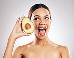Woman, beauty and avocado in studio, excited and health for wellness, facial glow and white background. Girl, model and healthy skin with fruit, makeup or cosmetics for self care, funny face or smile