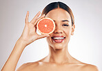 Grapefruit, skincare and woman smile in studio for natural cosmetic, eco or beauty on grey background. Citrus, facial and female model relax with fruit for vegan, detox and vitamin c for glowing skin