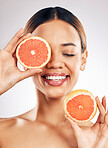 Happy, skincare and woman with grapefruit in studio for natural cosmetic, eco or beauty on grey background. Citrus, facial and female model relax with fruit for skin, detox and vitamin c or collagen