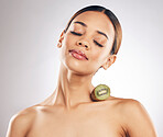 Natural, beauty and woman with kiwi for skincare in studio for vegan or eco friendly cosmetic on grey background. Skin, wellness and female model relax with fruit for anti aging, antioxidants or glow