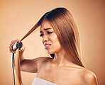 Woman with flat iron, hair care fail and worried about heat damage with hairloss isolated on studio background. Electric straightener, female model with anxiety about keratin treatment and hairstyle