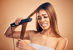 Woman with flat iron, hair care mistake and worried about heat damage with hairloss on studio background. Electric straightener, female model with anxiety about keratin treatment fail and hairstyle