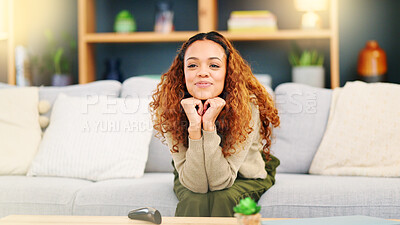 Lady laughing at comedy movie on her online subscription via wifi while sitting on her sofa at home. Young woman switches on tv using remote and enjoys stand up comedy relaxing on the couch indoors
