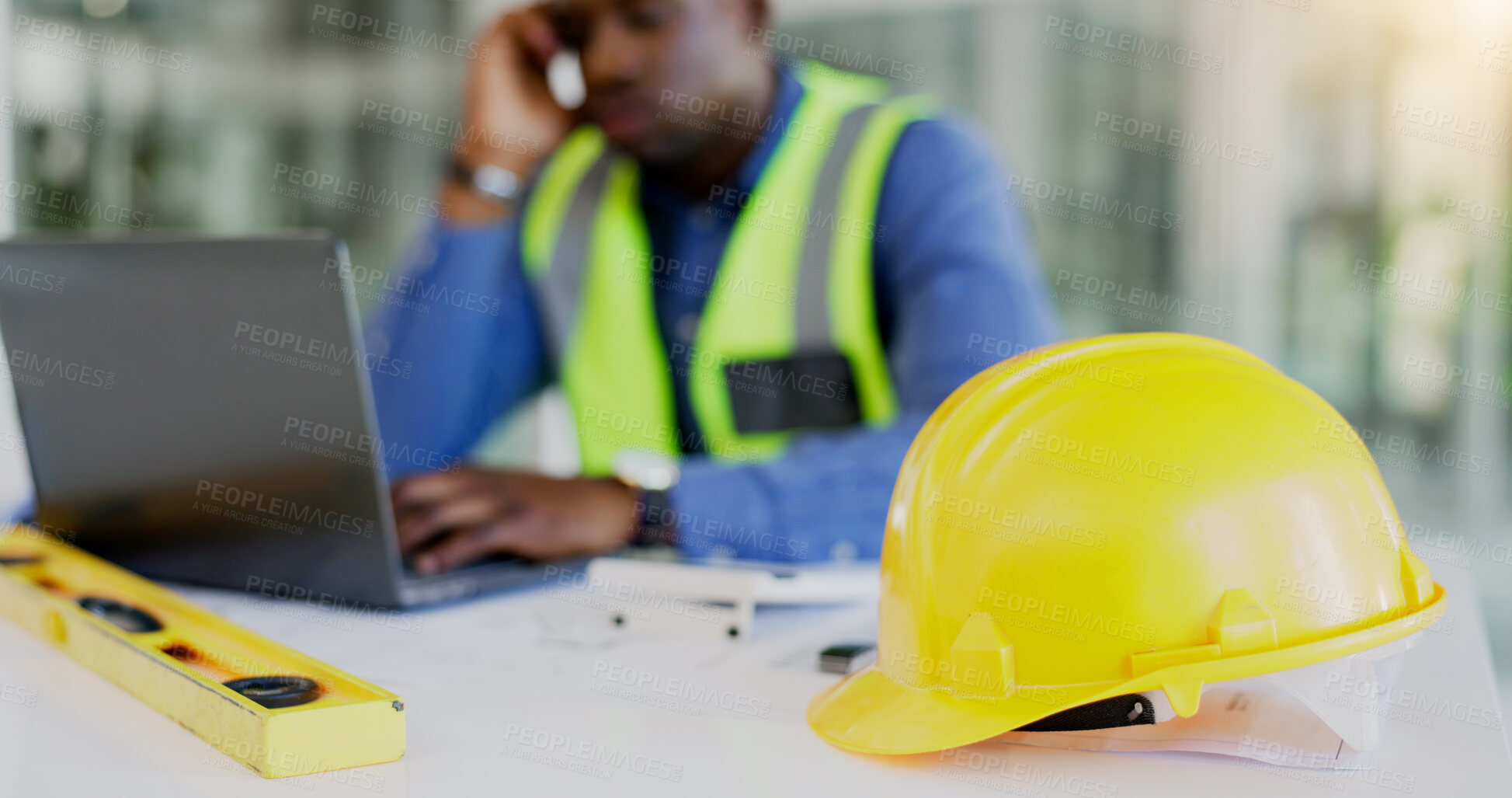 Buy stock photo Engineering, construction tools and architect with helmet on desk with break from project, worksite or renovation. African, person or foreman with laptop to review of plans, building or real estate 