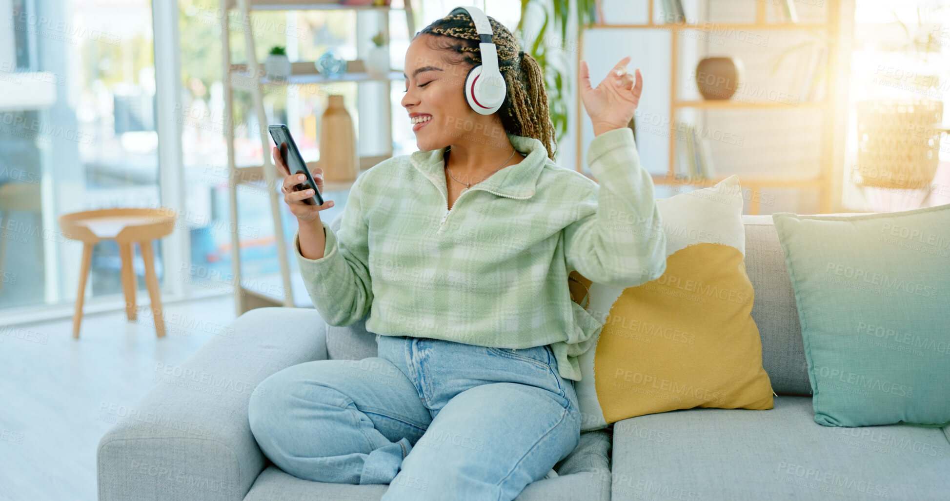 Buy stock photo Phone, sofa and happy woman on music headphones in home living room for dancing. Mobile, radio and African person listening to podcast, audio and sound for freedom, celebration and streaming online