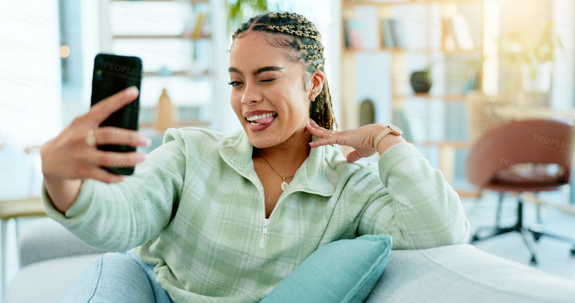 Buy stock photo Selfie, woman or phone with tongue out for profile picture, social media or internet post with wink on sofa in living room. Face, person or smartphone with emoji or goofy expression on couch or relax