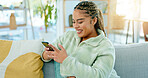 Black woman on sofa with smile, phone and coffee surfing internet, social media or web in living room. Relax, reading email or typing text, happy gen z girl on couch with smartphone on break with cup