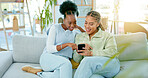 Phone, sofa and friends browsing on social media, the internet or mobile app together at home. Happy, conversation and women scrolling on a cellphone while relaxing in the living room at their house.