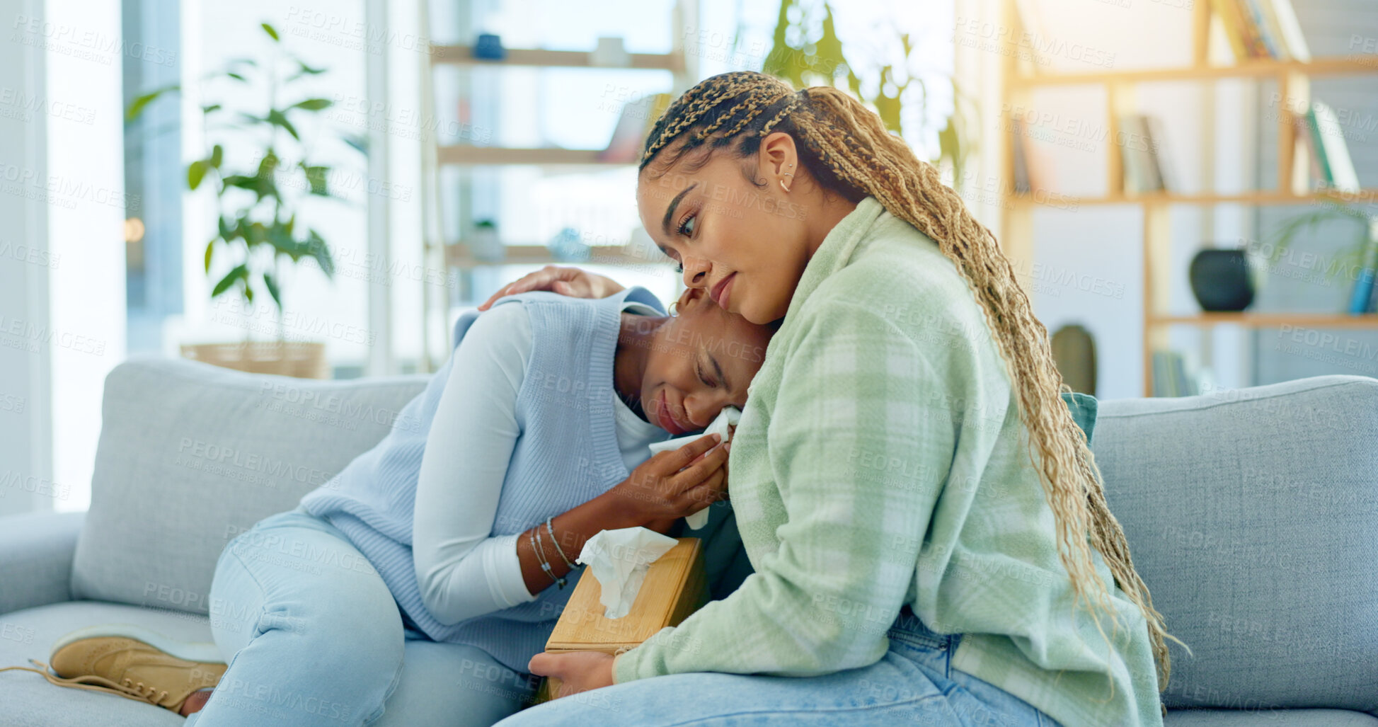 Buy stock photo Depression, empathy and support with black woman friends on a sofa in the living room of a home together. Sad, mental health and a young person crying into a tissue during loss, pain or grief