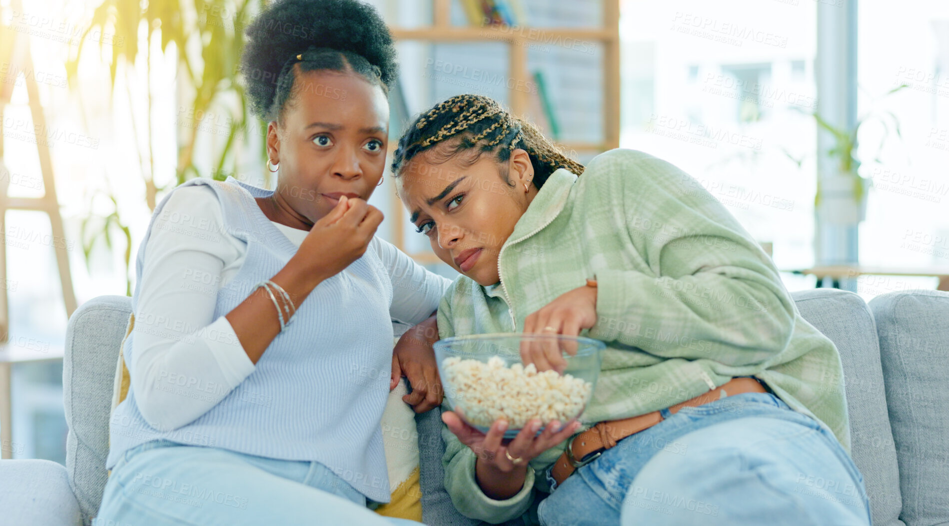 Buy stock photo Scary, movie and friends on sofa in living room with popcorn, snack or delicious in house. Black woman, people and together by watching tv, horror or film with expression on face by sitting on couch