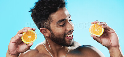 Orange, skincare and face of man in studio for beauty, wellness and citrus treatment on blue background. Fruit, facial and portrait of indian male model excited for organic vitamin c skin cosmetics